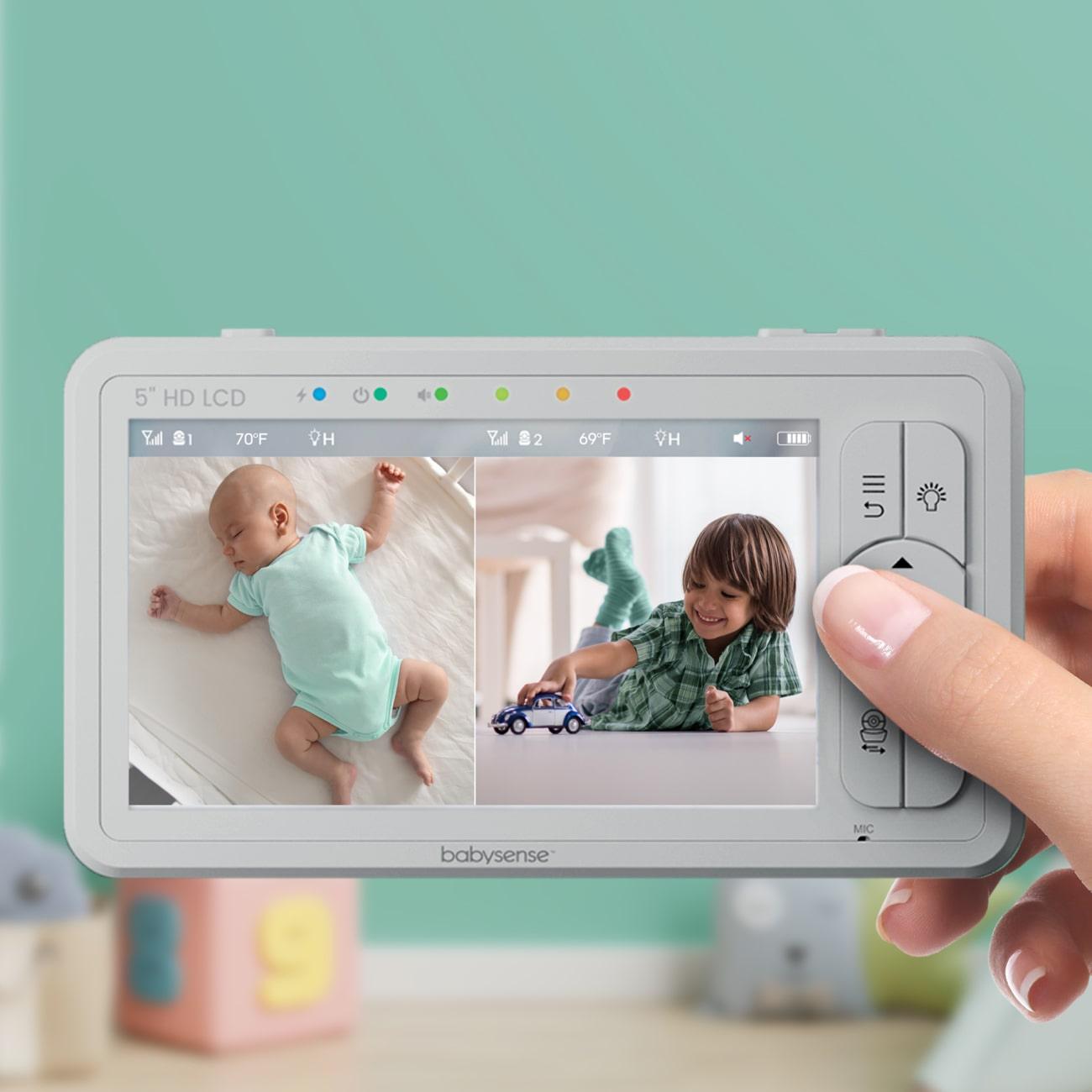 A person holds a Babysense 5" HD LCD monitor displaying a sleeping infant and a toddler playing, showcasing the best non wifi baby monitor for multi-room viewing