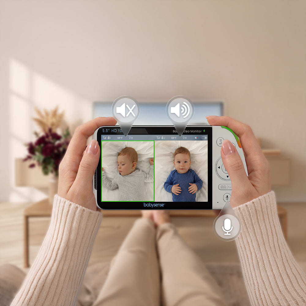 Person holding a smartphone with a baby monitor app displaying two babies, with a blurred indoor background.
